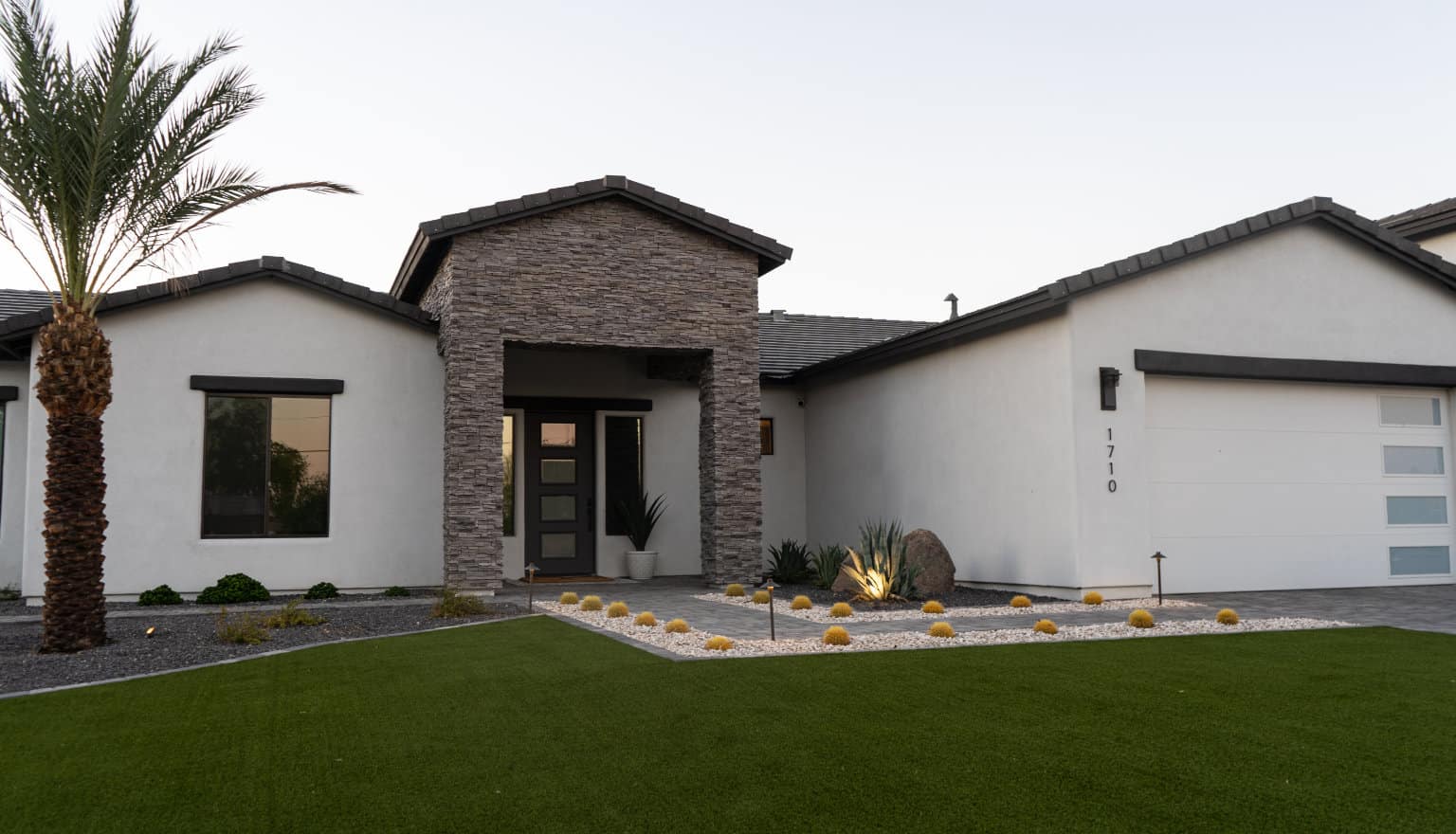 front yard with grass, rocks, plants, bushes and lighting