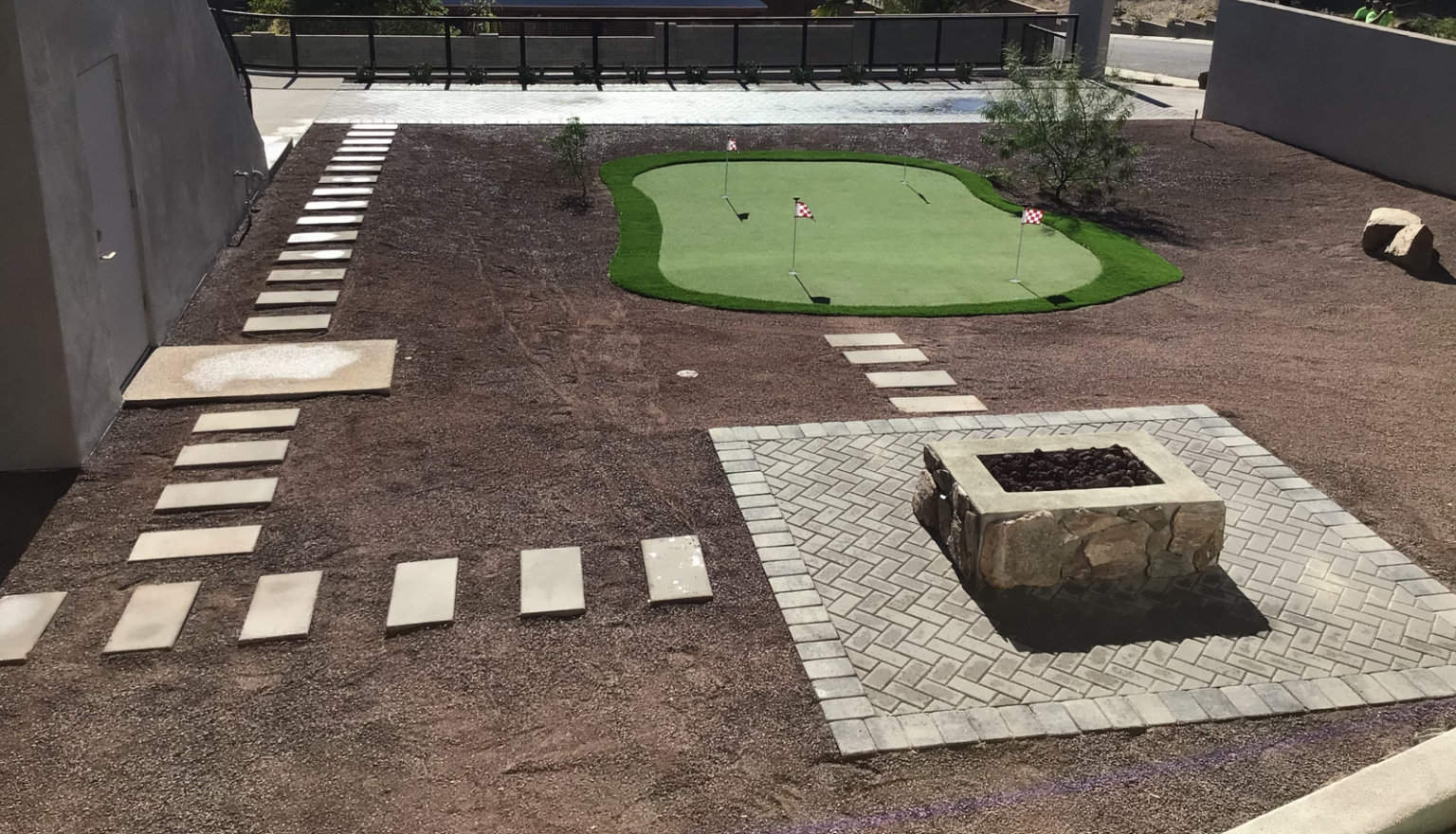 mini-golf course surrounded by rocks, pavers and a custom stone fireplace